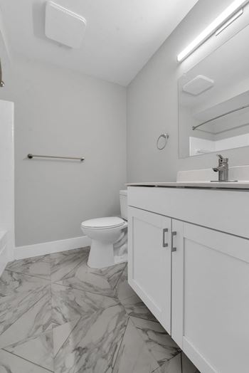 A white toilet sits in a bathroom with a marble floor.